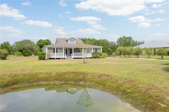 View of front of house featuring covered porch, a front yard, and a water view