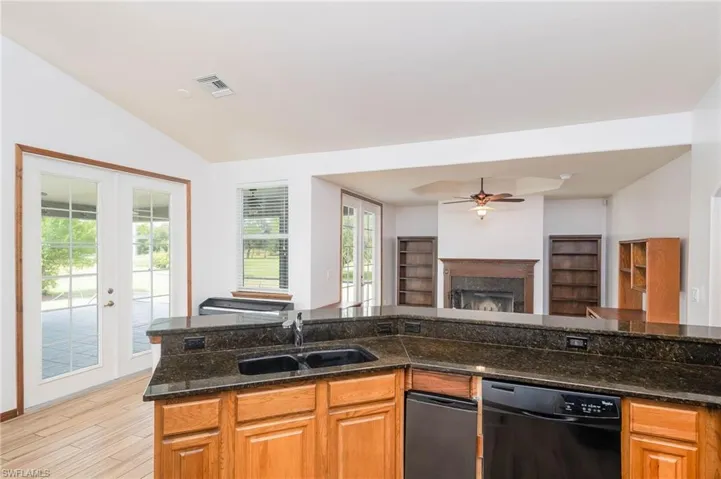 Kitchen with a sink, dishwasher, open floor plan, vaulted ceiling, and french doors