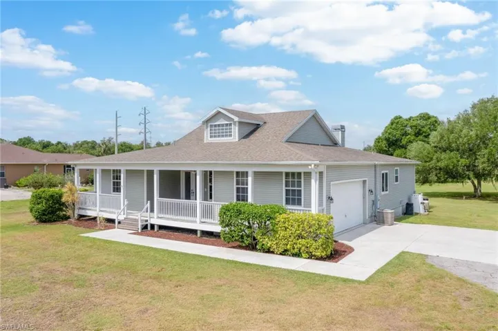 View of front of property featuring covered porch, driveway, an attached garage, a shingled roof, and a front yard