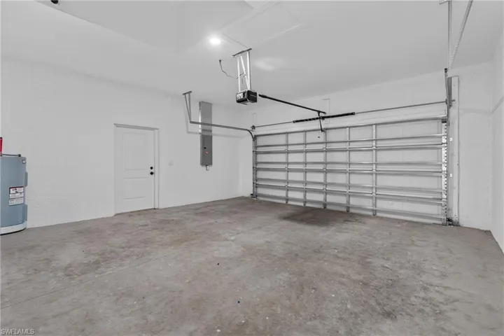 Garage with water heater, a garage door opener, and electric panel
