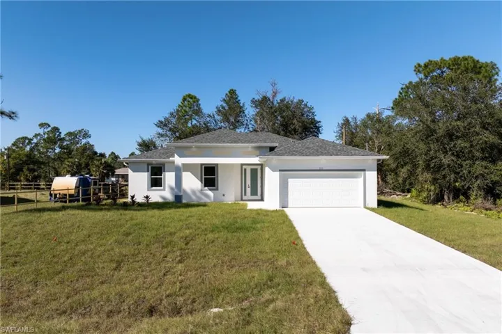 Prairie-style home with a garage, concrete driveway, stucco siding, and roof with shingles