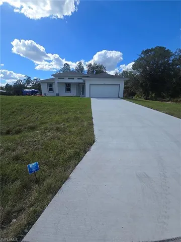 Ranch-style home with concrete driveway, a front yard, an attached garage, and stucco siding
