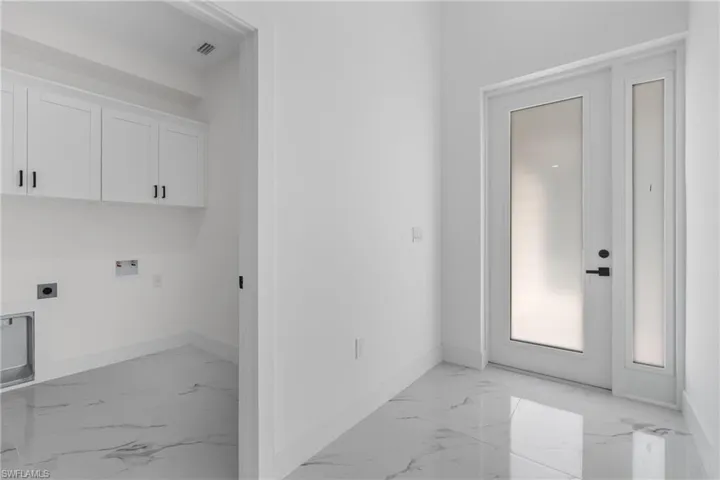 Laundry room with light marble finish floors, washer hookup, electric dryer hookup, and cabinet space