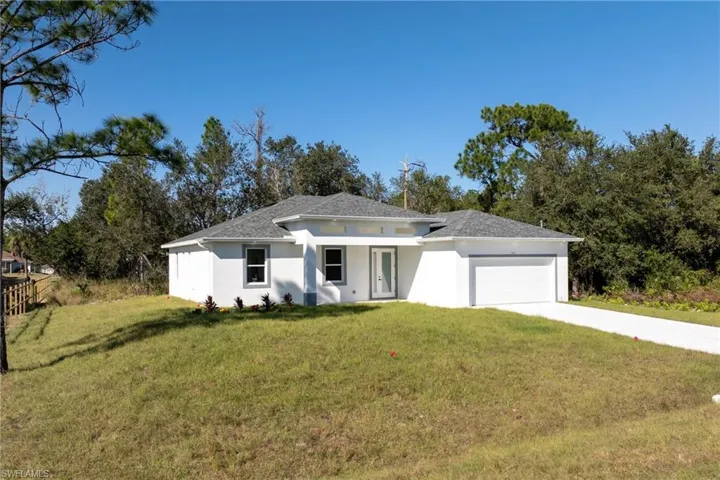 Prairie-style house with a front lawn, concrete driveway, stucco siding, an attached garage, and a shingled roof