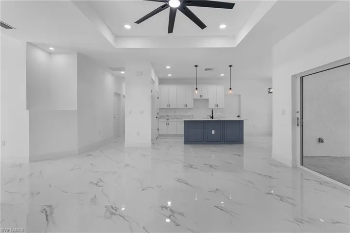 Unfurnished living room featuring recessed lighting, a raised ceiling, ceiling fan, and light marble finish floors