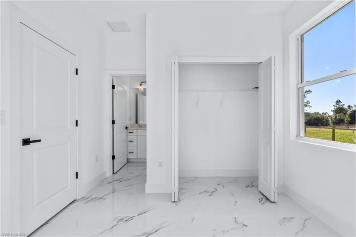Unfurnished bedroom with ensuite bath, light marble finish flooring, and a closet