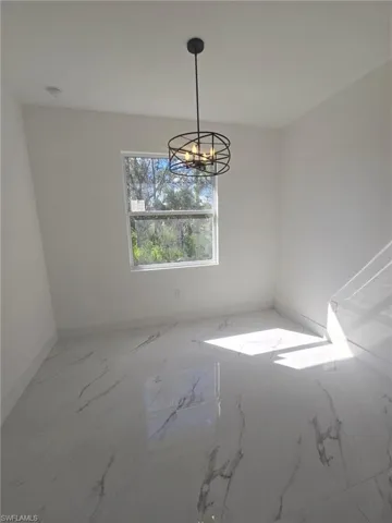 Unfurnished dining area featuring a chandelier and marble finish floors