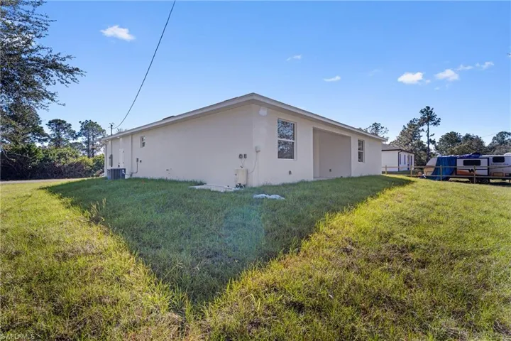 View of side of home featuring a lawn and stucco siding