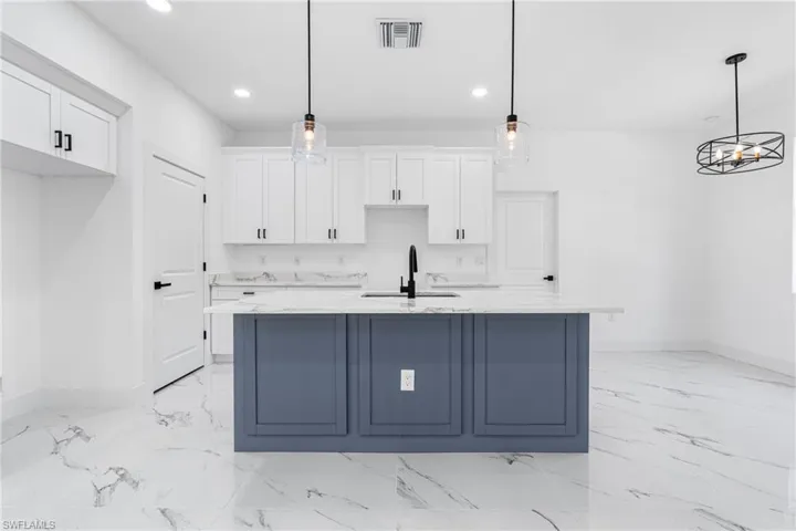 Kitchen with white cabinetry, light stone counters, decorative light fixtures, and recessed lighting