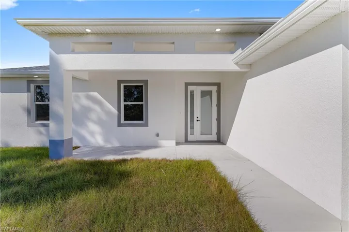 Doorway to property featuring stucco siding and a lawn