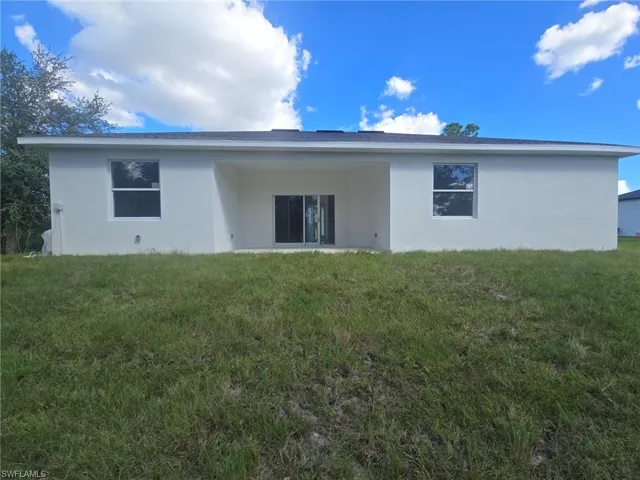 Rear view of property with a patio, stucco siding, and a yard