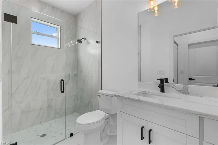 Bathroom featuring a marble finish shower and vanity