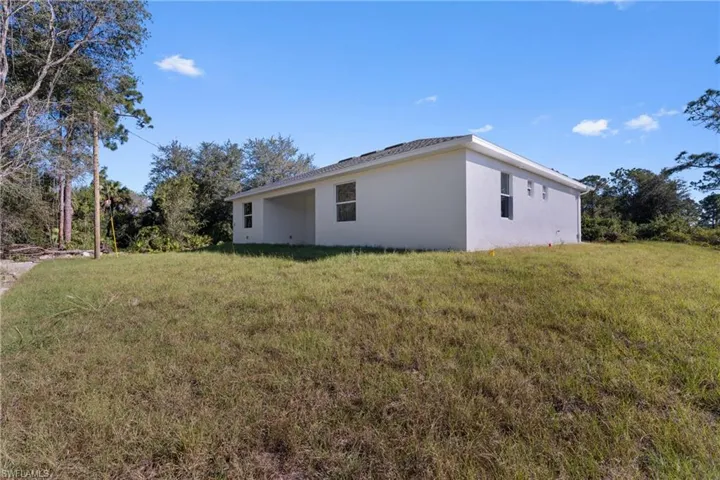 View of side of home with a lawn and stucco siding