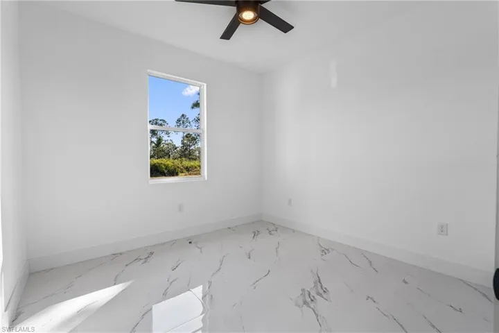 Empty room with marble finish floors and a ceiling fan