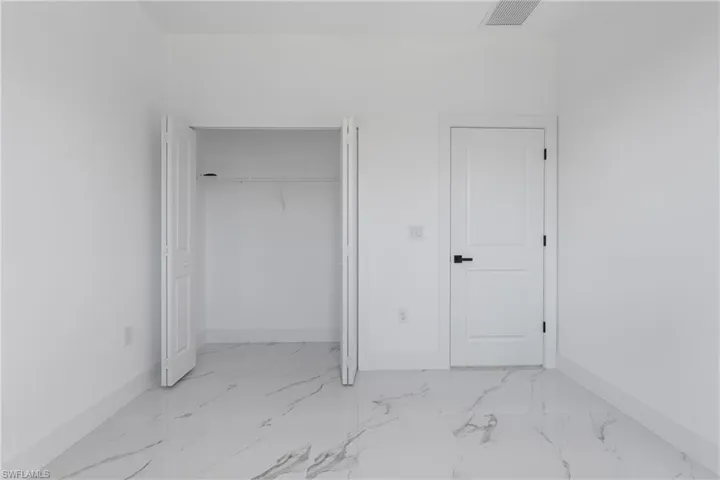 Unfurnished bedroom featuring light marble finish flooring and a closet