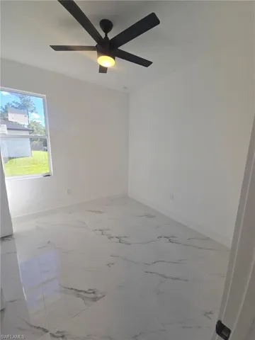 Spare room with light marble finish floors and a ceiling fan