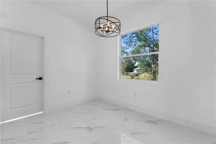 Unfurnished room featuring light marble finish floors and a chandelier