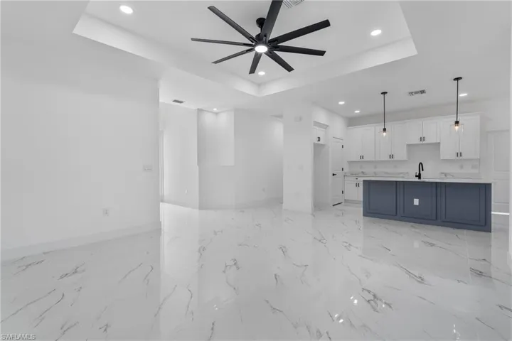 Unfurnished living room with a raised ceiling, recessed lighting, and ceiling fan