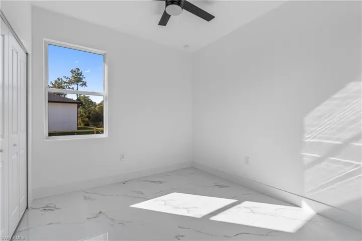 Empty room featuring light marble finish flooring and ceiling fan