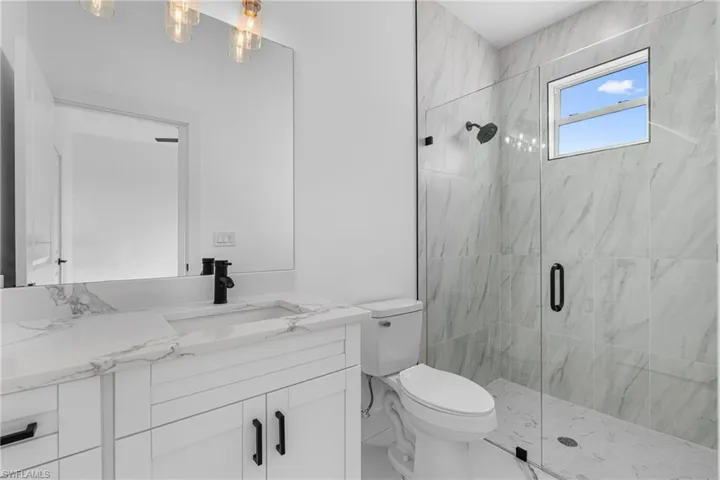 Bathroom featuring vanity and a marble finish shower