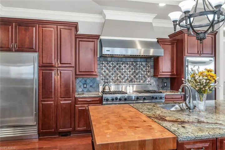 Island Chef Kitchen gas stove, granite and butcher block counter top.