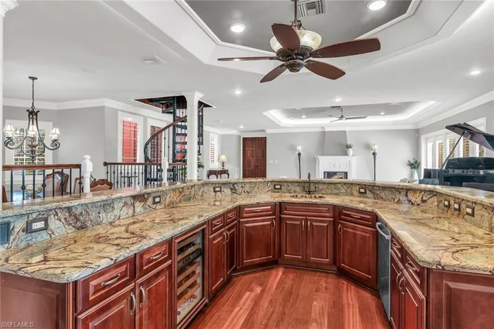 Central wet bar with dishwasher, sink and wine coller, granite countertop.