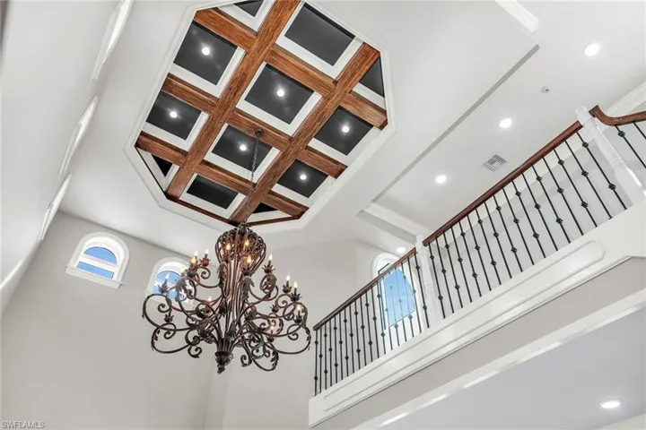 Detailed view of coffered ceiling, beamed ceiling, recessed lighting, ornamental molding, and a chandelier