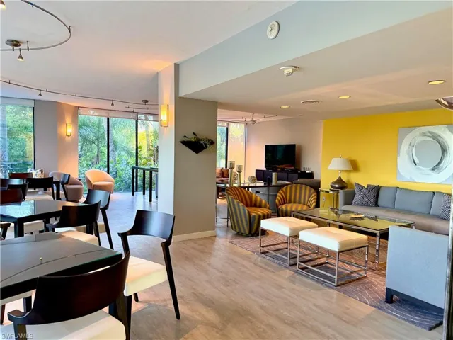 Open-concept living area with large windows, recessed lighting, track lighting, and light wood-finish flooring