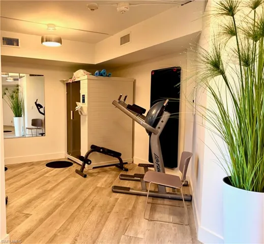 Dedicated fitness space featuring wood-finish flooring and a full-length mirrored wall