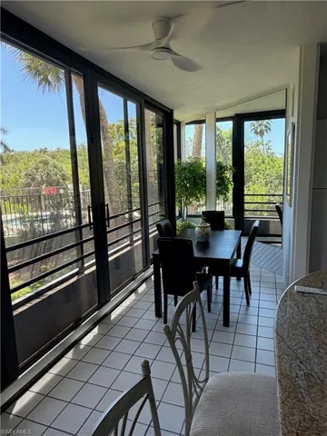 Sunroom featuring extensive full-height windows, a white ceiling fan, and white square tile flooring