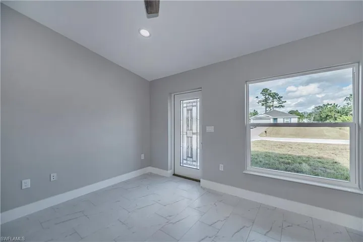 Empty room with lofted ceiling and light tile floors