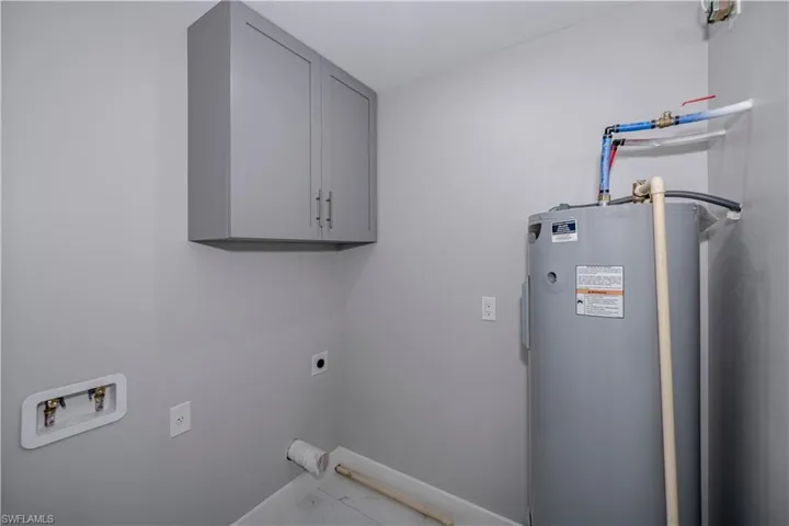 Laundry area with cabinets, electric dryer hookup, water heater, tile floors, and hookup for a washing machine