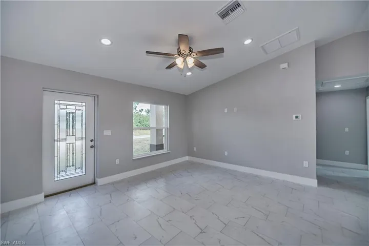 Unfurnished room featuring ceiling fan, lofted ceiling, and light tile floors