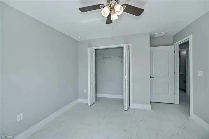 Unfurnished bedroom featuring a closet, ceiling fan, and light tile floors