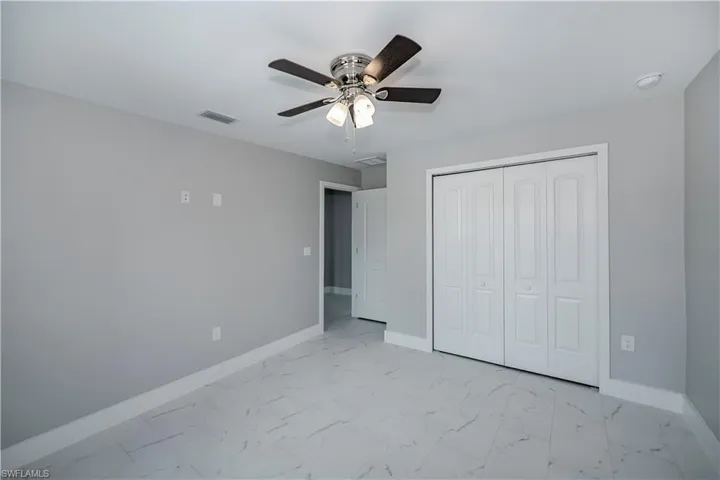 Unfurnished bedroom with a closet, ceiling fan, and light tile flooring