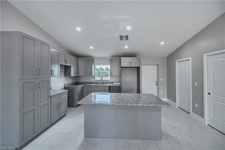 Kitchen featuring a center island, sink, lofted ceiling, and light tile floors