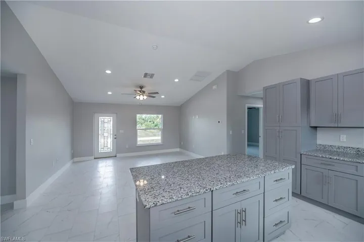 Kitchen with a center island, ceiling fan, vaulted ceiling, and light tile floors