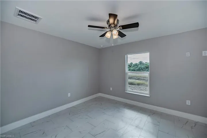 Tiled spare room featuring ceiling fan