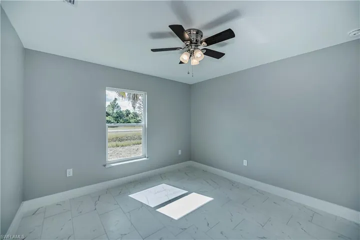 Empty room with ceiling fan and light tile flooring