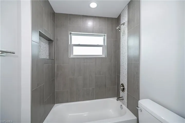 Bathroom with tiled shower / bath and toilet