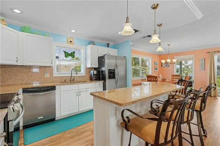 Kitchen featuring tasteful backsplash, appliances with stainless steel finishes, light stone countertops, light hardwood / wood-style flooring, and sink