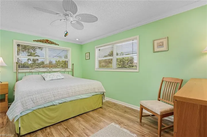 Bedroom featuring ceiling fan, light wood-type flooring, and multiple windows