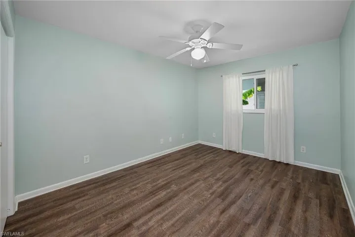 Empty room with dark hardwood / wood-style floors and ceiling fan