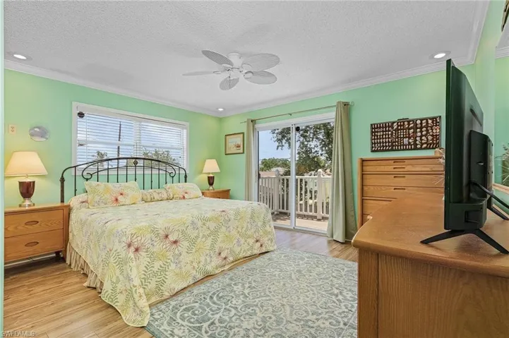 Bedroom featuring ceiling fan, light wood-type flooring, ornamental molding, and access to exterior