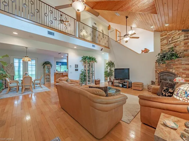 Living area with ceiling fan, wood ceiling, a fireplace, light wood finished floors, and high vaulted ceiling