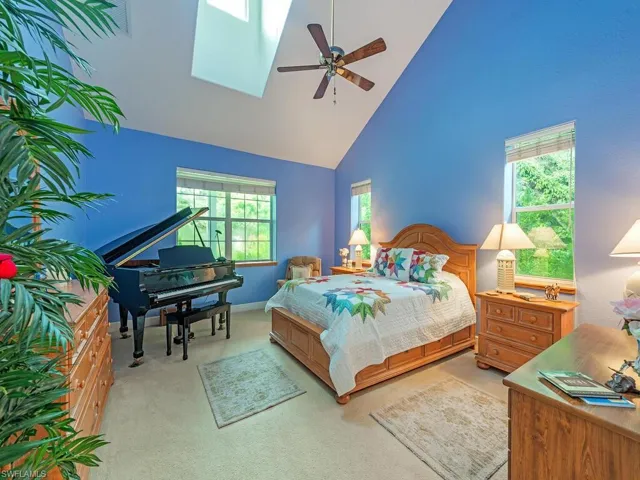 Bedroom with high vaulted ceiling, light colored carpet, and a ceiling fan