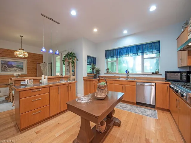 Kitchen featuring appliances with stainless steel finishes, light wood-type flooring, decorative light fixtures, recessed lighting, and a center island