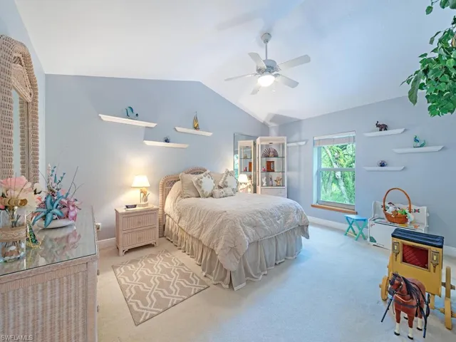 Bedroom with vaulted ceiling, carpet flooring, and a ceiling fan