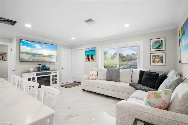 Living room with light marble finish flooring, crown molding, and recessed lighting