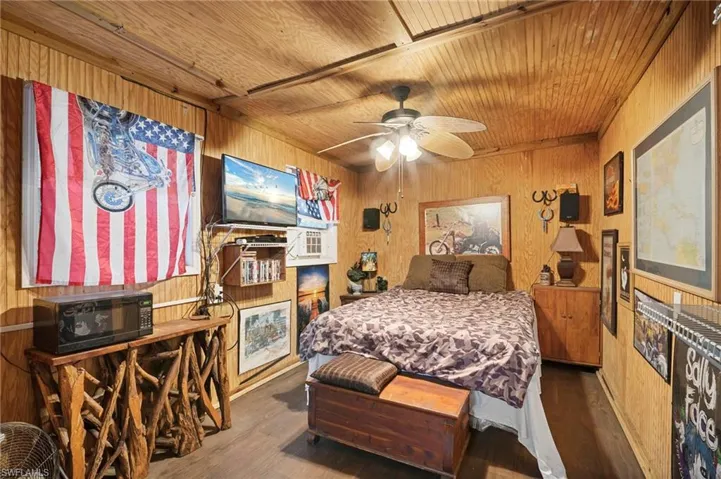 Bedroom featuring wood walls, wood finished floors, wood ceiling, and ceiling fan